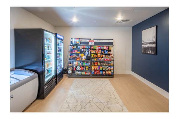 A room with a vending machine and a fridge.